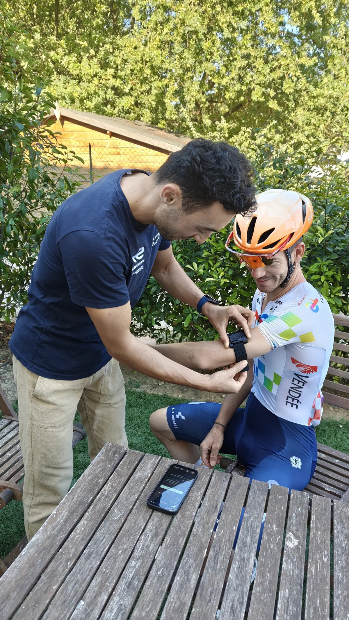 Robin Meyer posant un capteur de sueur Flowbio sur le bras d'un coureur du Team TotalEnergies