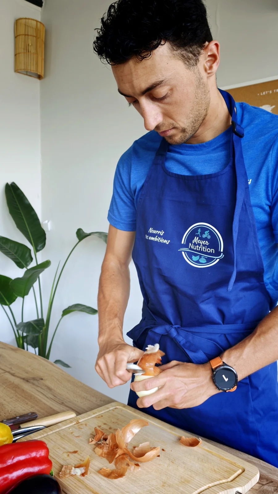 Robin Meyer en tablier Meyer Nutrition épluche un oignon en cuisine